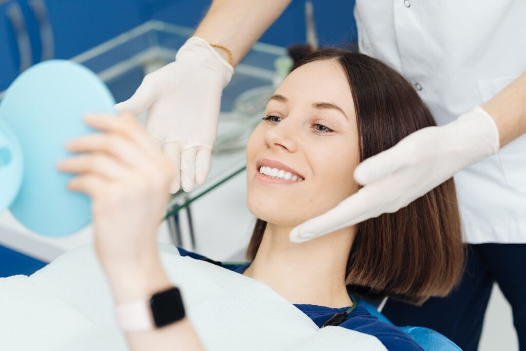 Perfect smile, woman looking in the mirror. Visit at the dentist