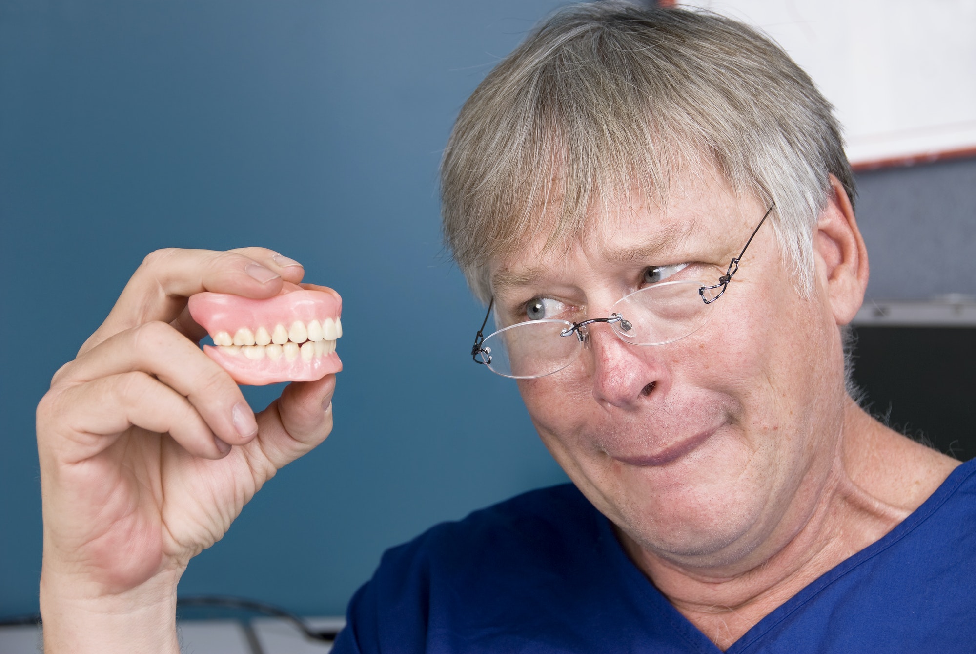 Man examining his new dentures, expertly crafted by Lance Family Dental, showcasing quality dental prosthetics.