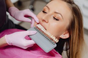 Dentist comparing tooth shades with a patient during a cosmetic dentistry consultation